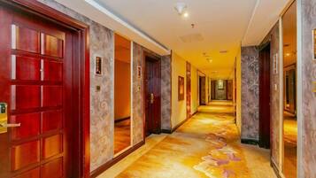 A hotel corridor with multiple doors, a carpeted floor, and a light fixture on the ceiling.