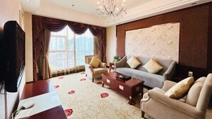 Una sala de estar con sofá, sillones, una mesa de centro y televisor.