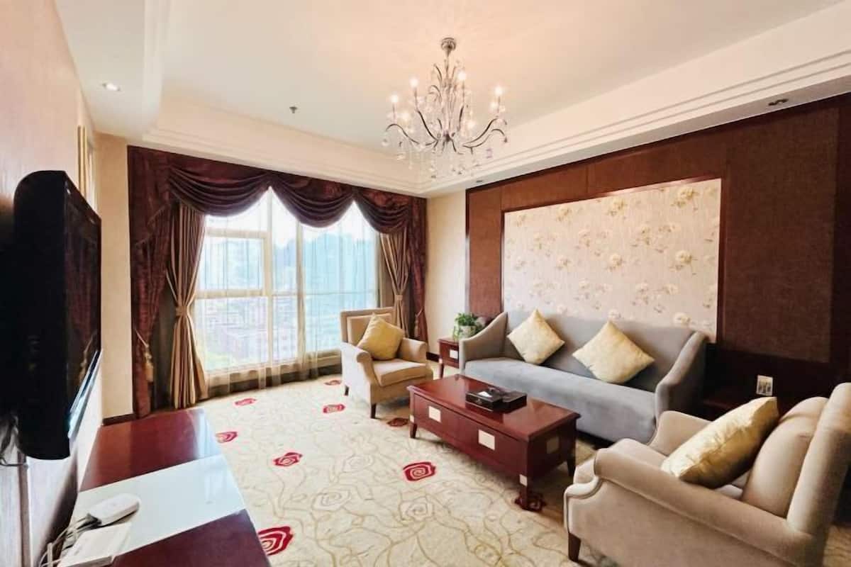 Een woonkamer met een bank, fauteuils, een salontafel en een televisie.