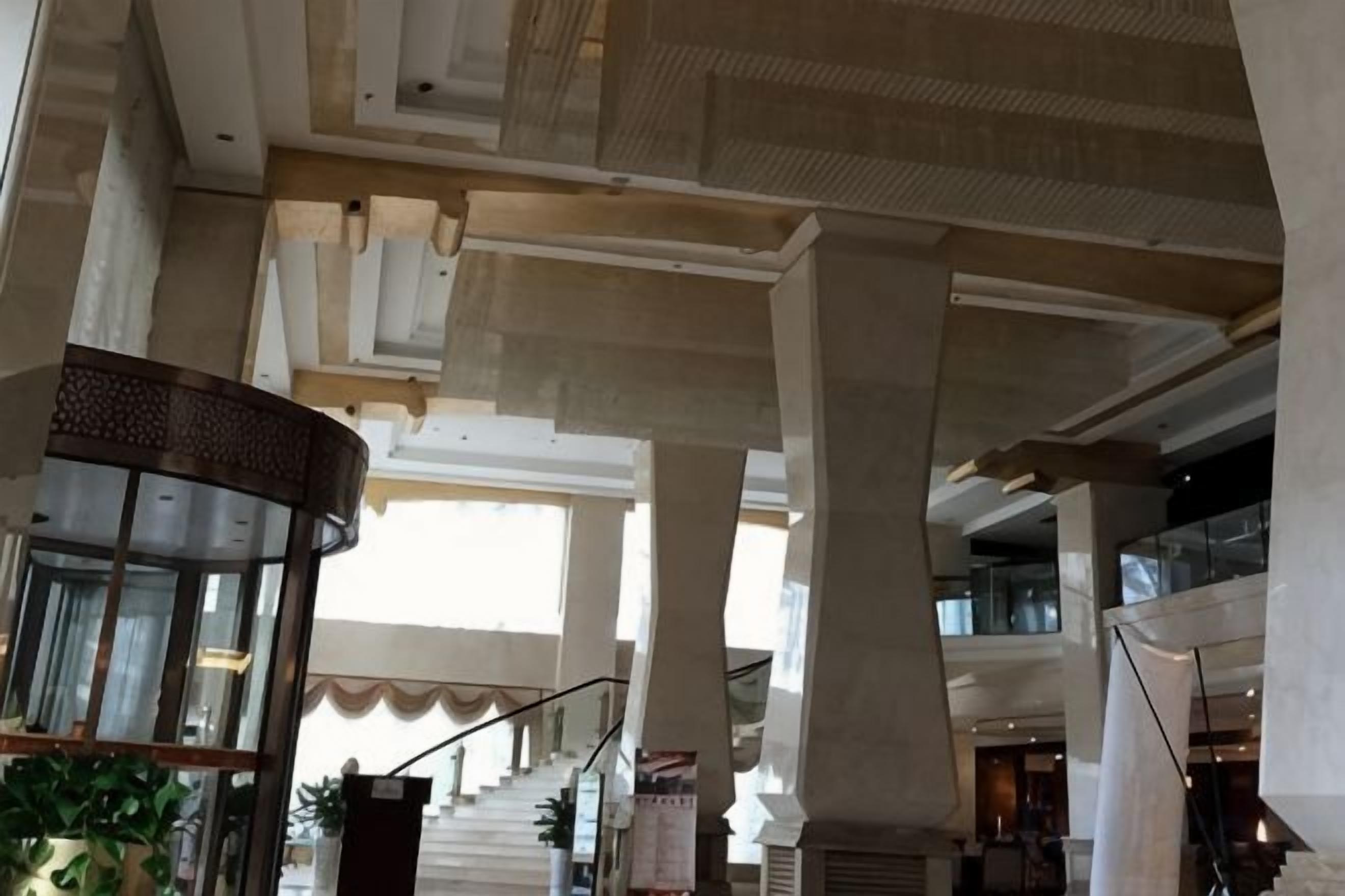 A spacious interior with high ceilings, large columns, and a staircase leading to an upper level.