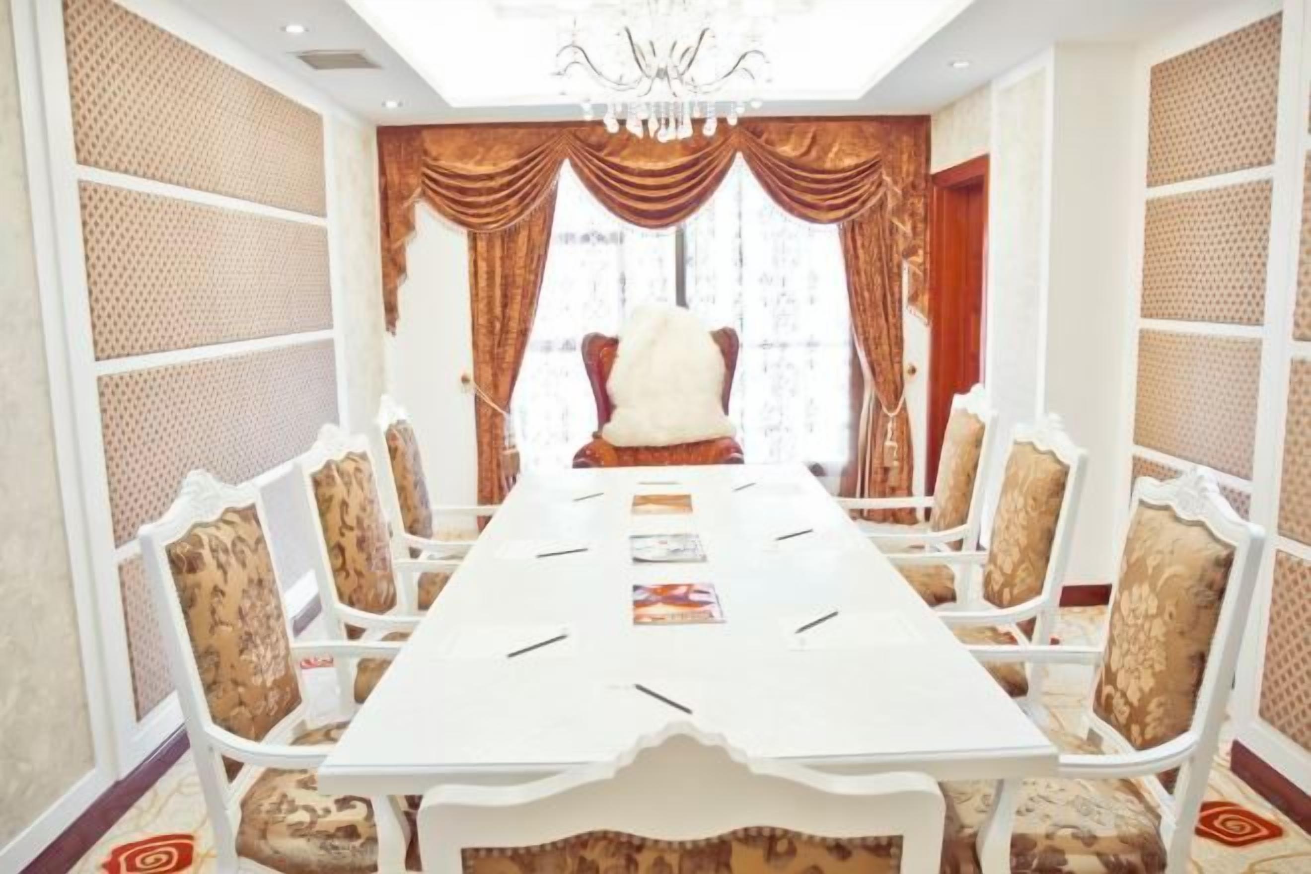 A conference room with a long table, chairs, and a large chair at the end.