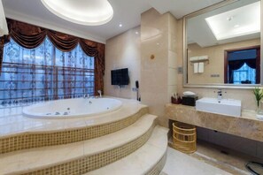 Un bany amb una banyera gran, un lavabo, un mirall i una televisió.