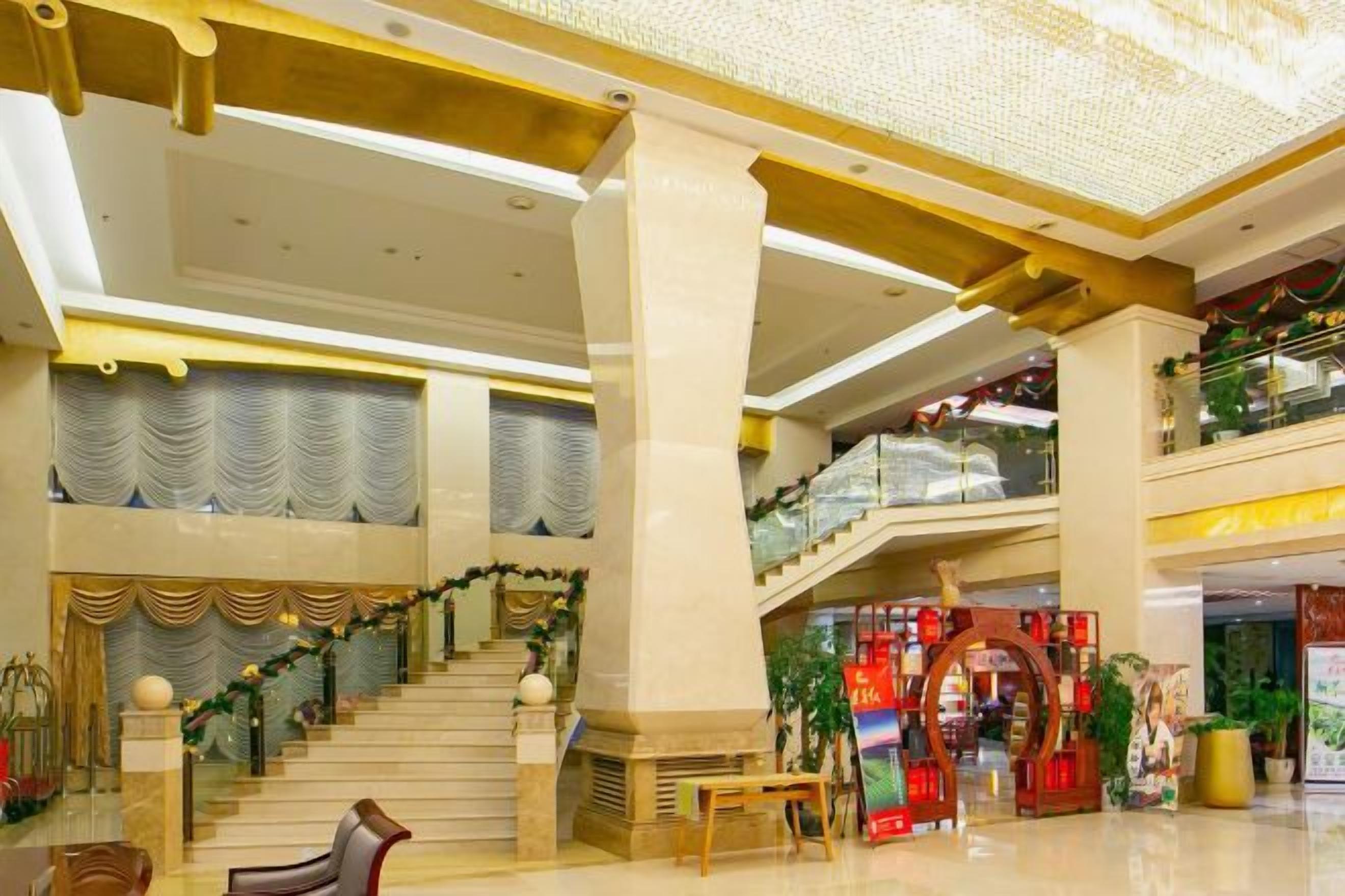 A spacious lobby with a grand staircase, a reception desk, and a Christmas display.