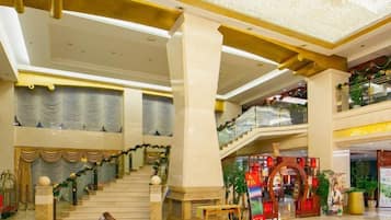 A spacious lobby with a grand staircase, a reception desk, and a Christmas display.
