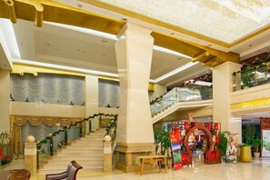 Eine geräumige Lobby mit einer imposanten Treppe, einem Empfangsbereich und einer Weihnachtsausstellung.