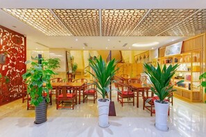 Un hall de hotel con mostrador de recepción, zona de estar y una estantería.