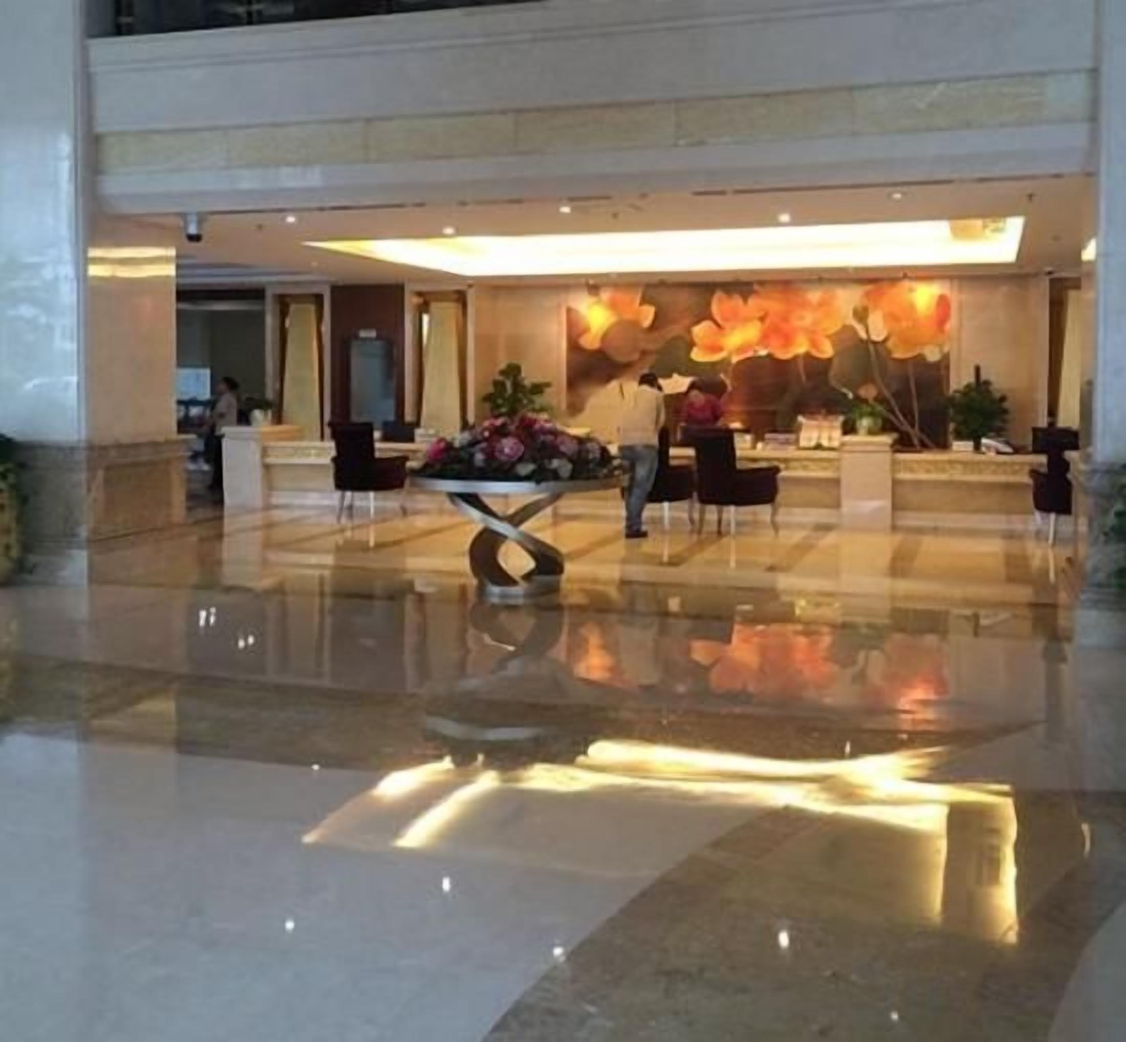 A lobby with a reception desk, seating area, and a decorative wall.