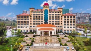 A large hotel with multiple floors, a central courtyard, and a red dome. - Tianju Caohai Holiday Hotel (Weining)