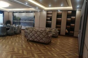Interior moderno com piso em padrão herringbone, sofá, área de refeições e uma grande janela com vista para as montanhas.