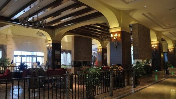 A spacious lobby with high ceilings, arched columns, and a central seating area. - Tianju Caohai Holiday Hotel (Weining)