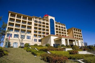 A multi-story hotel with a central atrium, a red dome, and a well-maintained garden.
