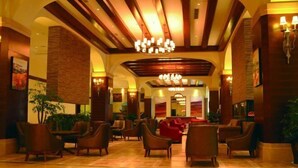 A spacious lobby with a high ceiling, chandeliers, and comfortable seating areas. - Tianju Caohai Holiday Hotel (Weining)