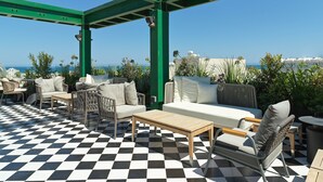 Una terrazza sul tetto con pavimento a scacchi, arredi da esterno e vista mare.