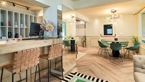 Una cucina moderna con un piano di lavoro in legno, sgabelli da bar e un'area pranzo con sedie verdi e un tavolo rotondo.