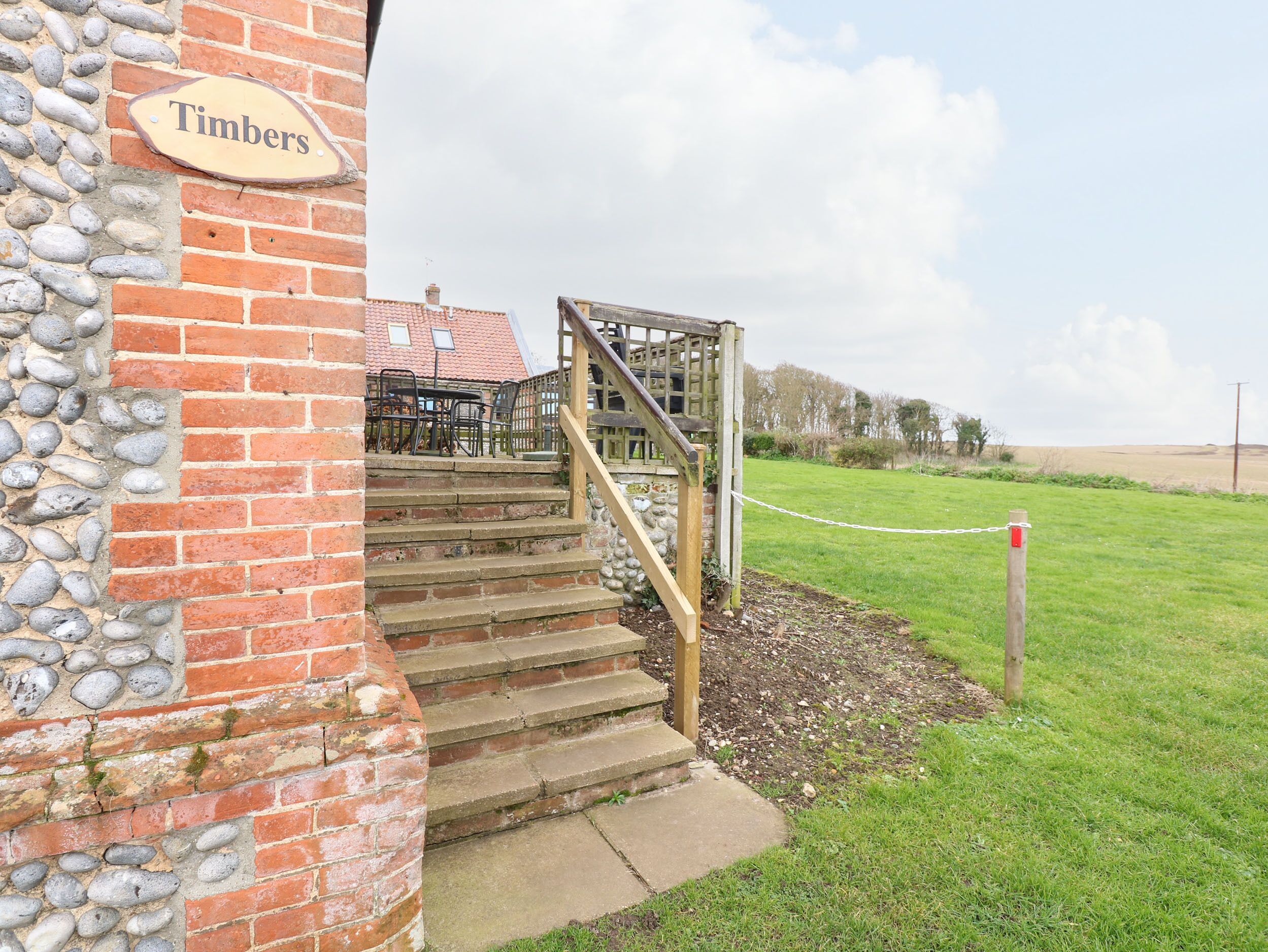 A brick building with a wooden staircase leading to a deck area.