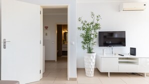 A modern living room with a white TV on a stand, a white cabinet, and a potted plant. - Kojima Lilac Apartament, Praia da Rocha, Portimao (Portimão)