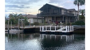 A two-story house with a balcony, a dock, and a small boat. - Beautiful Home with direct access to the gulf and private dock!  (Hernando Beach)