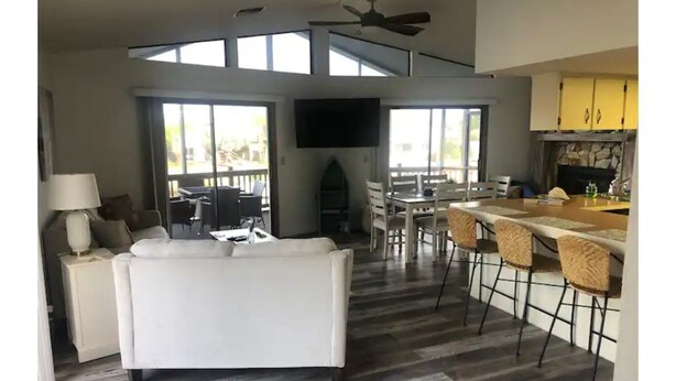 A spacious living area with a white sofa, a dining table with chairs, and a kitchen area with a bar. - Beautiful Home with direct access to the gulf and private dock!  (Hernando Beach)