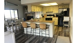 A modern kitchen with a central island, bar stools, and a dining area with a table and chairs. - Beautiful Home with direct access to the gulf and private dock!  (Hernando Beach)
