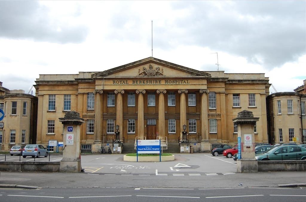 The Royal Berkshire Hospital building with classical architecture, a prominent entrance, and a parking area in front.