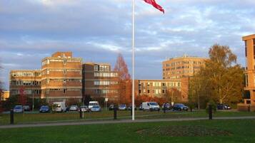 A building with multiple floors, a flagpole with a flag, and several parked cars.