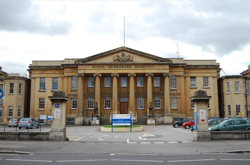 The Royal Berkshire Hospital building with classical architecture, a prominent entrance, and a parking area in front.