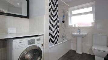 Bathtub, hair dryer, towels, shampoo