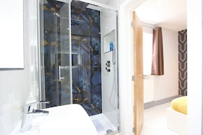 Une salle de bain moderne avec une douche à parois de verre, un lavabo blanc et un miroir.