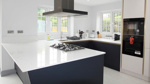 A modern kitchen with a central island, a built-in oven, and a range hood. - Elegant 4 Bed 3 Bath House & Parking by CozyNest (Reading)