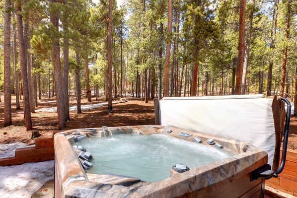 Un jacuzzi en un área boscosa con altos pinos.