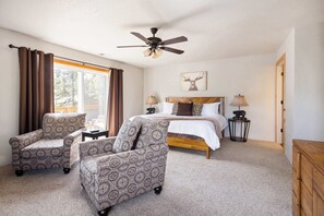 A bedroom with a bed, two chairs, a ceiling fan, a lamp, and a deer painting on the wall. - Hot Tub, Arcade games, and Mountain Views Retreat! (Black Hawk)