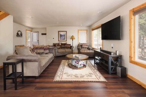 A living room with a sofa, armchair, coffee table, and a flat-screen TV. - Hot Tub, Arcade games, and Mountain Views Retreat! (Black Hawk)