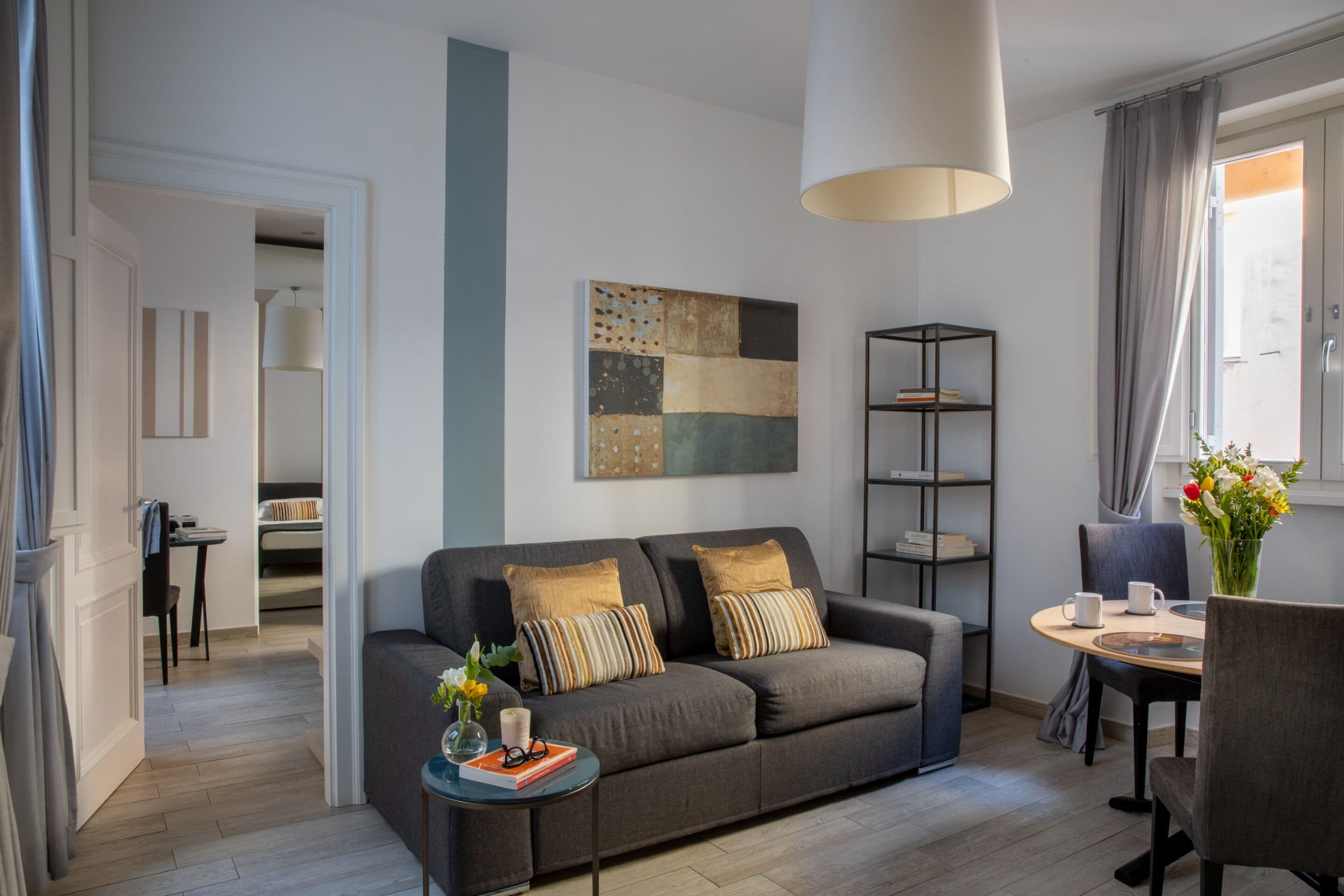 A modern living room with a grey sofa, a coffee table, and a bookshelf.