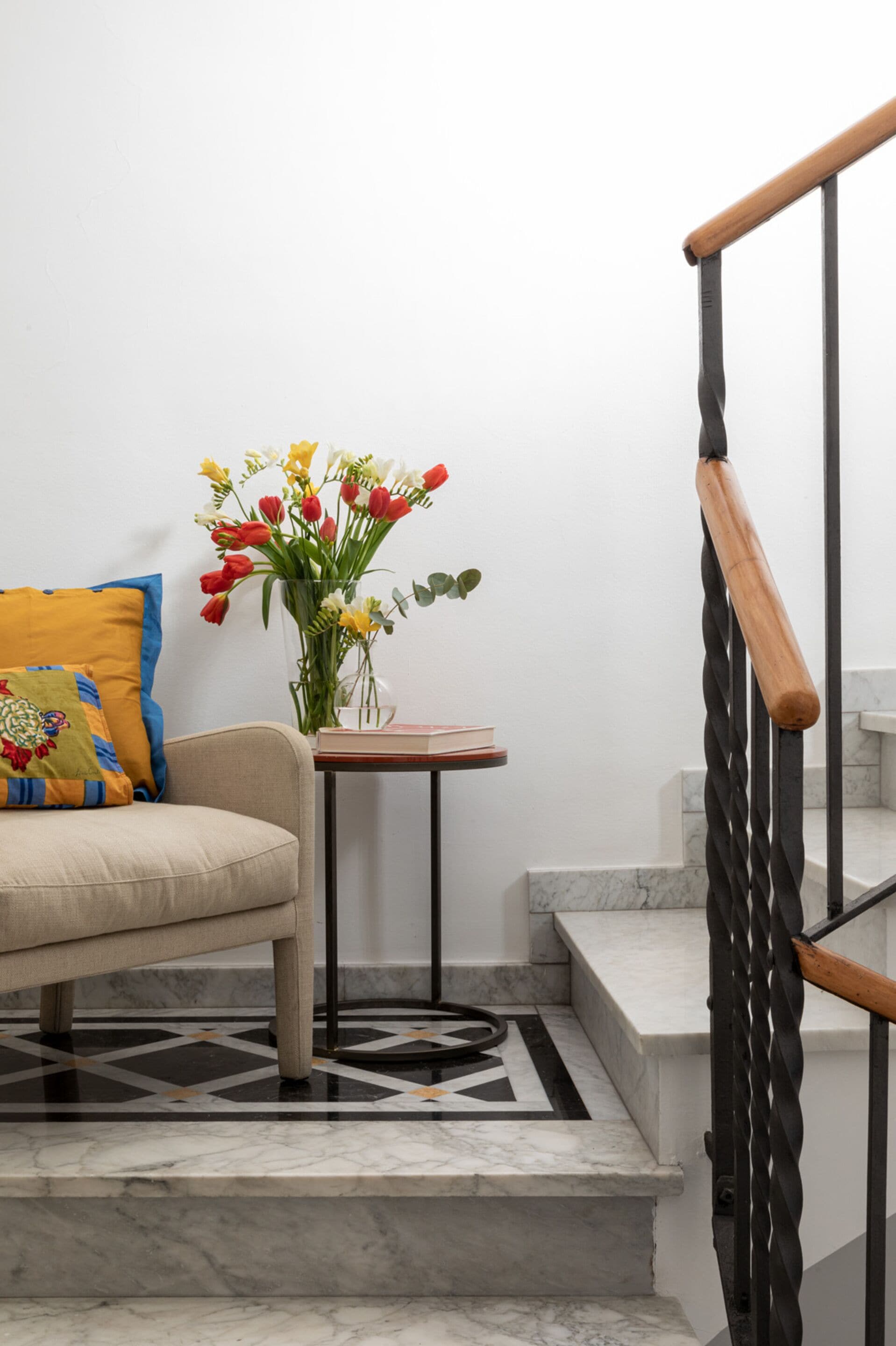 A staircase with a wooden handrail and a marble floor.
