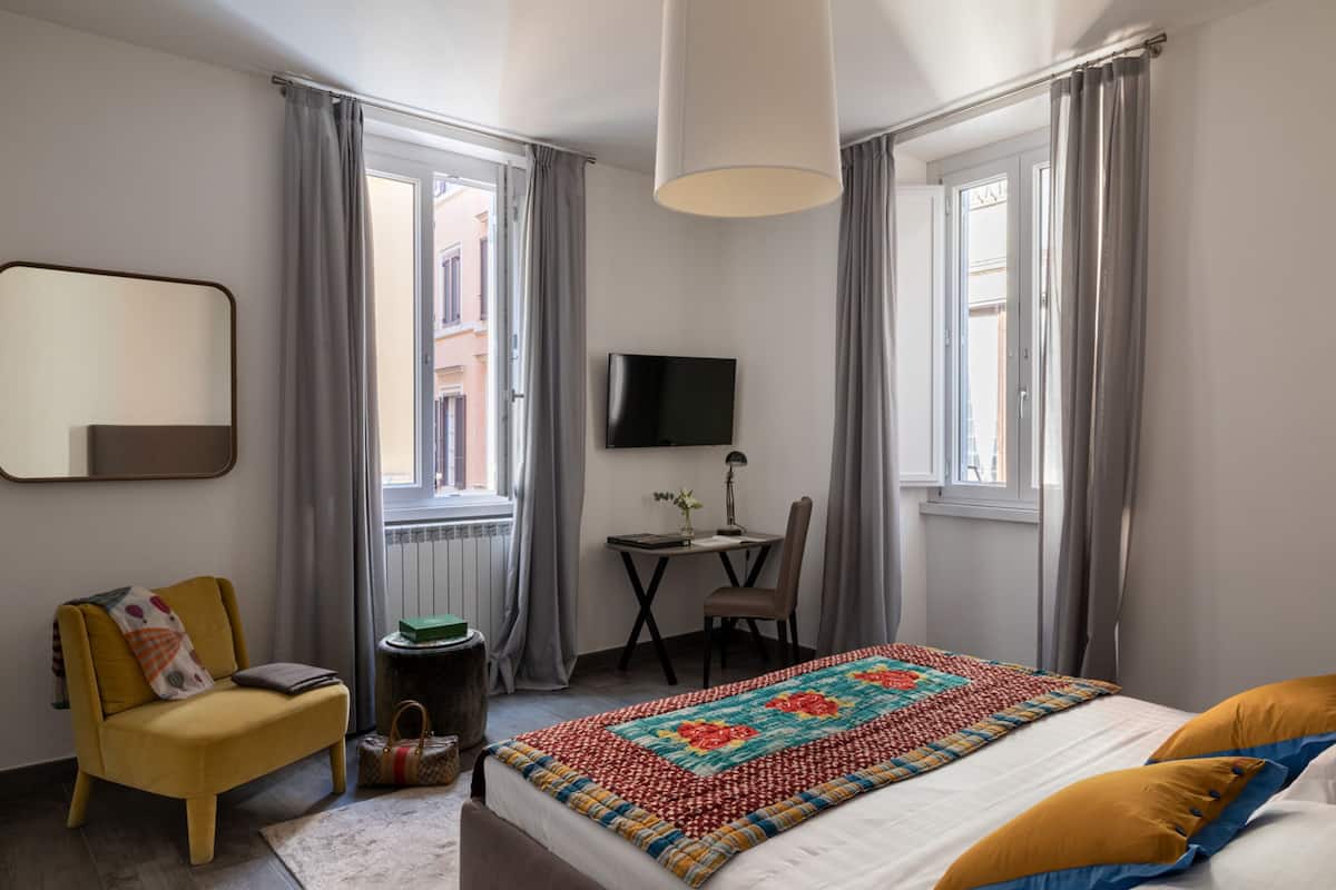 Une chambre d’hôtel équipée d’un lit, d’un bureau, d’une chaise, d’une télévision et d’une fenêtre avec des rideaux.