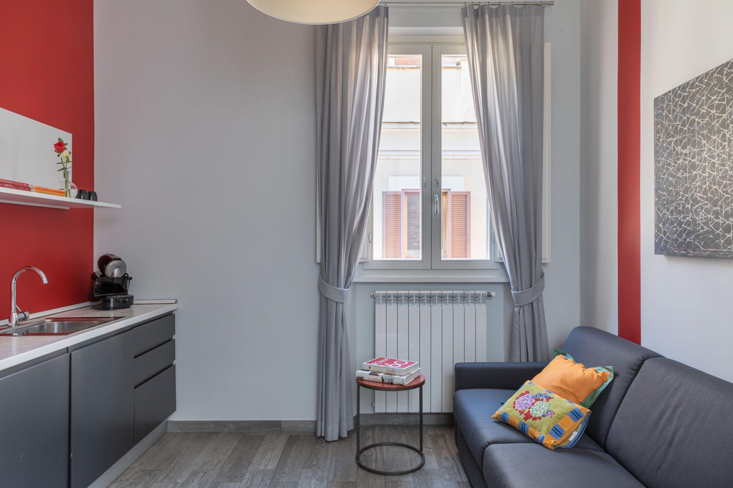 A compact living space with a kitchenette, a sofa, and a window with curtains.