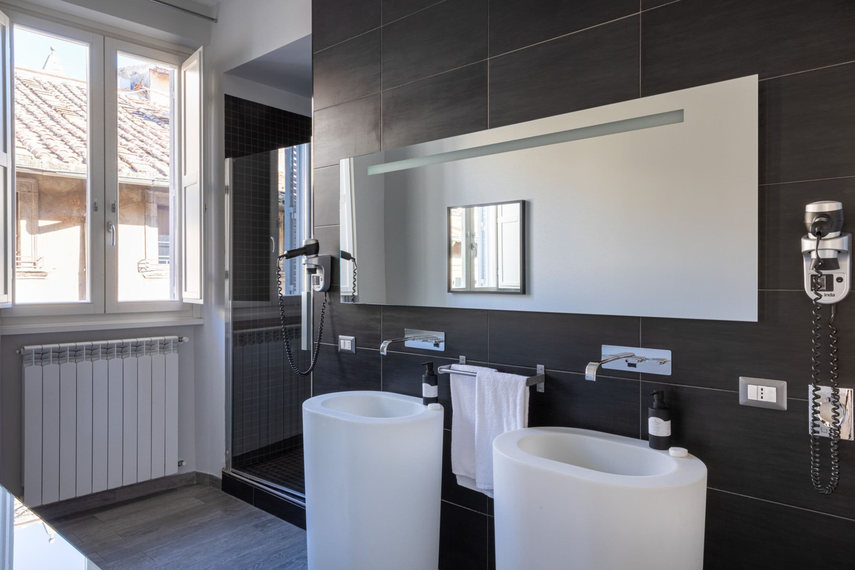 Een moderne badkamer met twee grote wasbakken, een spiegel en een douche.