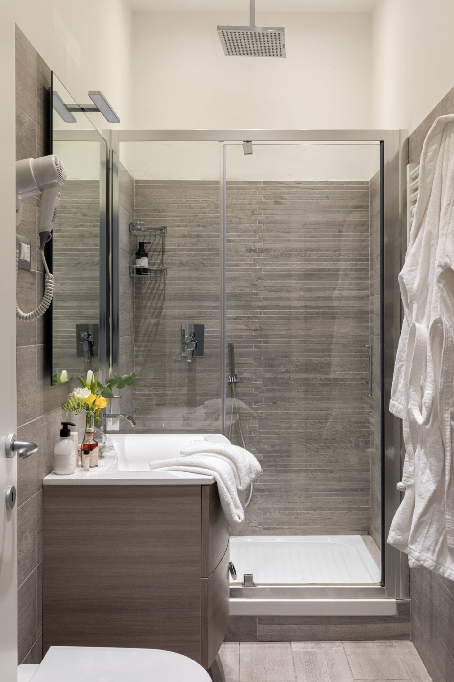 A modern bathroom with a glass-enclosed shower, a vanity with a mirror, and a toilet.