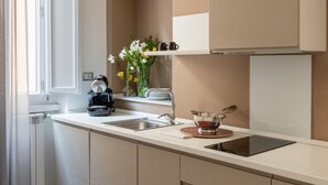 Una cocina moderna con encimera blanca, armarios color beige y una ventana con cortinas.