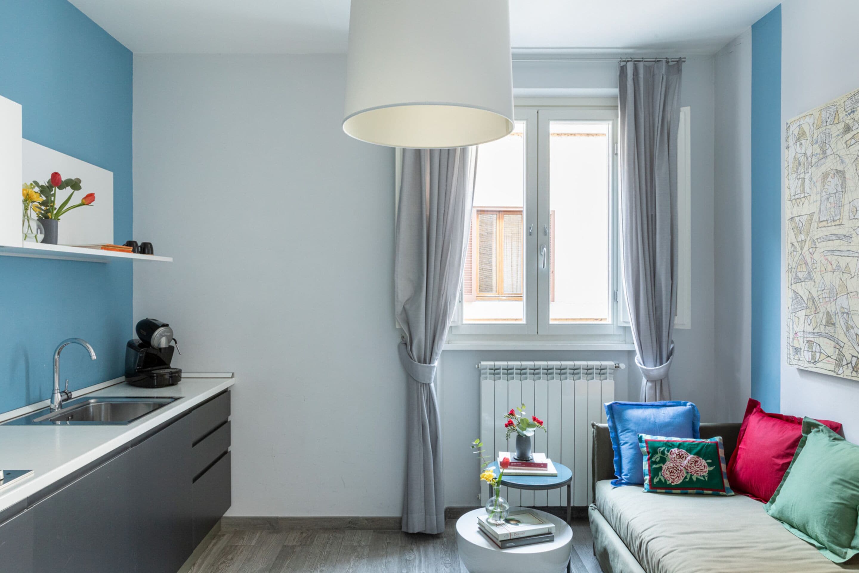 Un espace de vie compact comprenant un coin cuisine, un coin repas et un espace détente avec un canapé et des coussins.