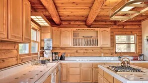 A wooden cabin-style kitchen with a central island, wooden cabinets, and a built-in stove. - Stunning Cabin with Great Views and blissful sunsets! (Sonora)