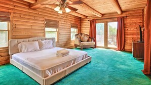 A log cabin bedroom with a large bed, a ceiling fan, and a view of the outdoors. - Stunning Cabin with Great Views and blissful sunsets! (Sonora)