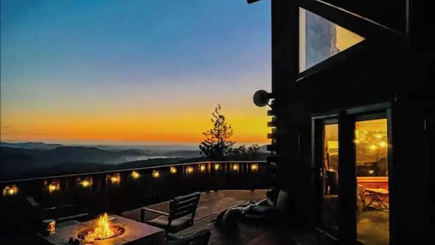 A deck with a fire pit and seating, overlooking a scenic view during sunset. - Stunning Cabin with Great Views and blissful sunsets! (Sonora)