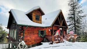 A wooden cabin with a steep roof, a porch, and a flag. - Stunning Cabin with Great Views and blissful sunsets! (Sonora)