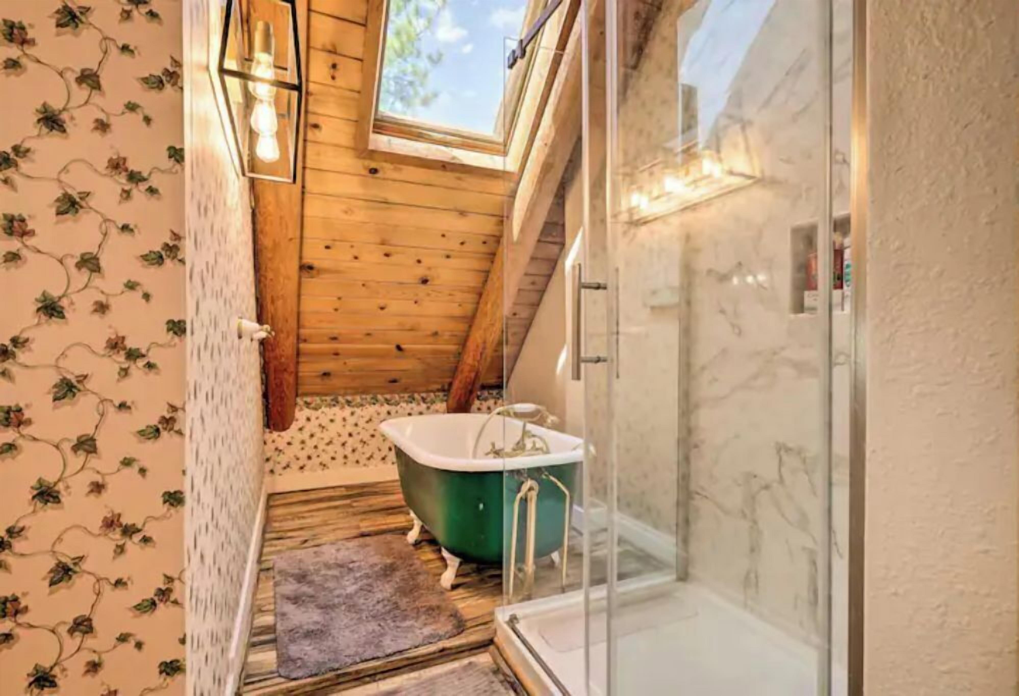 A bathroom with a clawfoot bathtub, a glass shower enclosure, and a skylight.