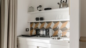 Une cuisine moderne équipée d’un four à micro-ondes, d’une bouilloire et d’une machine à café, le tout posé sur le plan de travail.