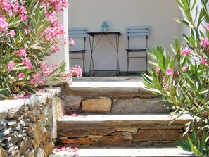 A stone staircase leading to a terrace with two blue chairs and a table.