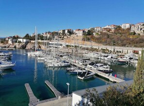 Un port de plaisance où sont amarrés de nombreux bateaux, une jetée qui s’avance dans l’eau et des bâtiments en arrière-plan.