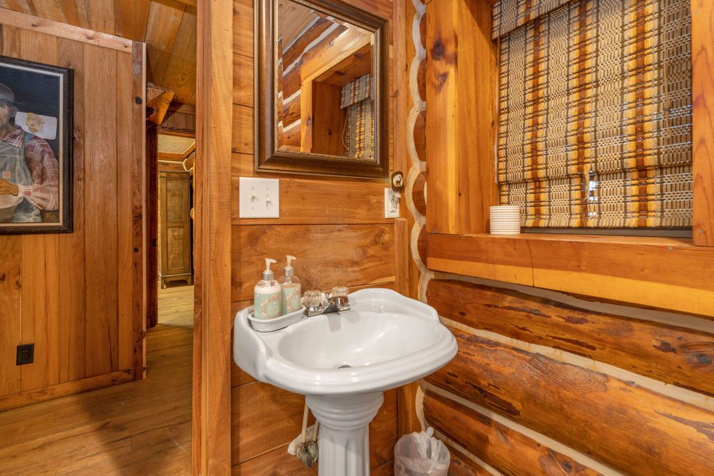 Ein Badezimmer in einer Holzhütte mit einem weißen Waschbecken, einem Spiegel und einem fenster mit Muster.