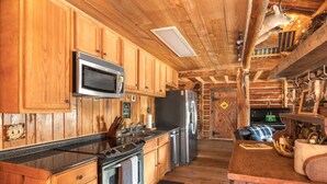 Une cuisine de style rustique, avec des éléments en bois, comprenant un four à micro-ondes, une cuisinière, un réfrigérateur et des placards en bois.
